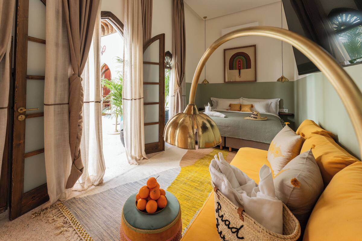 A bedroom with a bed, a bedside table, a lamp, and a window with curtains.