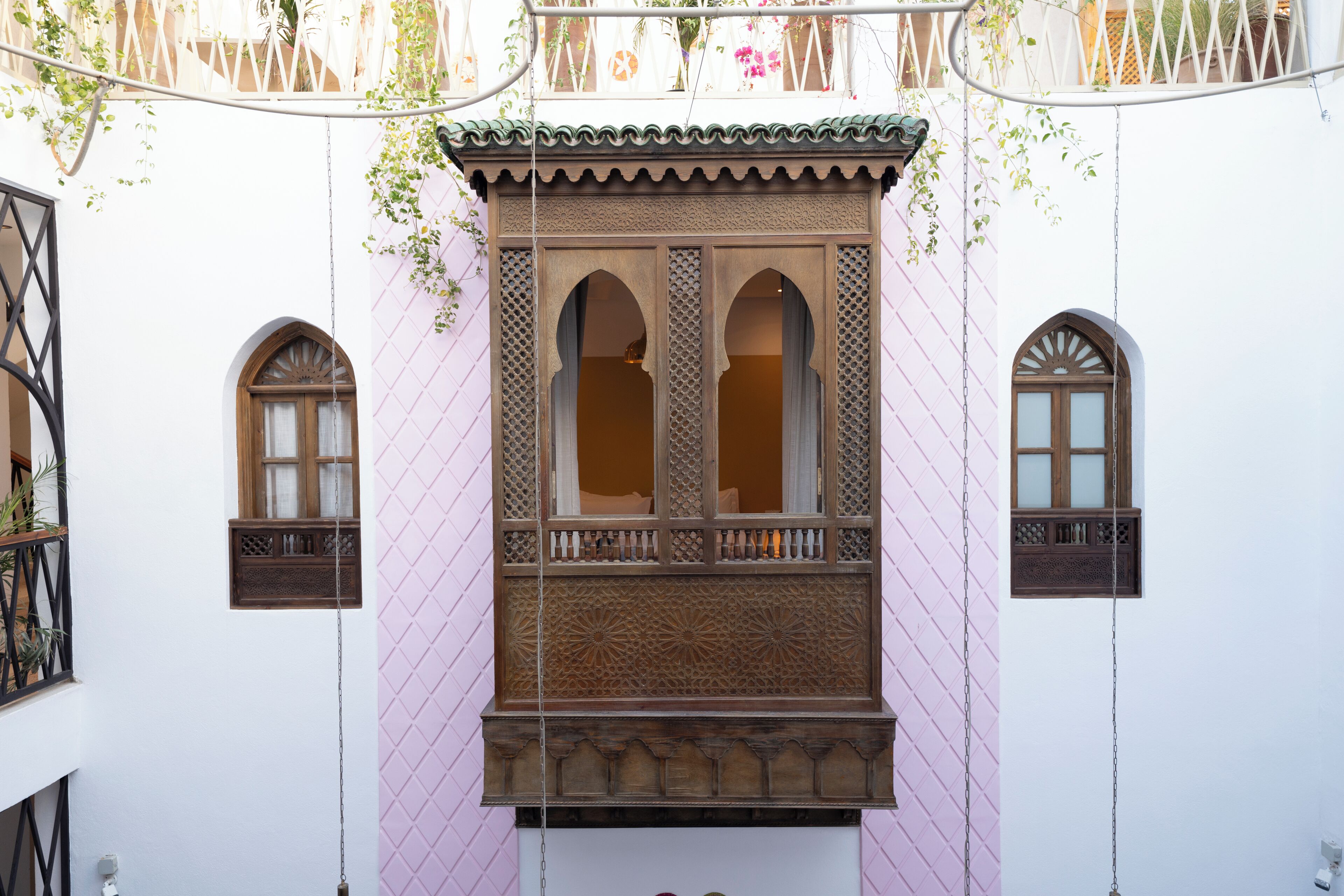 Edifici amb un balcó i talles de fusta ornamentals, i dues finestres d'arc a cada costat.