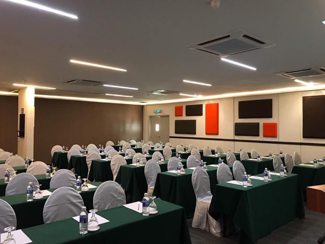 Un salón de conferencias con filas de mesas, sillas y botellas de agua.