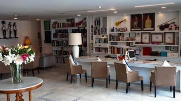 Ein modernes Wohnzimmer mit Couchtisch, Sesseln, Bücherregal und Schreibtisch inklusive Computer.
