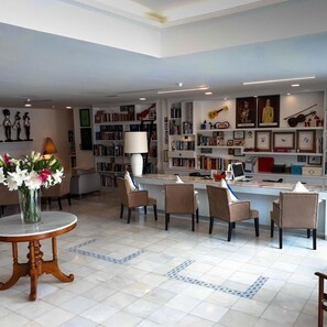 Een moderne woonkamer met een salontafel, stoelen, een boekenkast en een bureau met een computer.