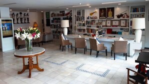 Eine Hotelhalle mit Empfangstresen, Sitzgelegenheiten und einem großen Bücherregal voller Bücher und dekorativer Gegenstände.