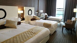 Ein Hotelzimmer mit zwei Betten, einer Sitzecke mit einem Sessel und einem großen Fenster.
