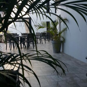 An indoor dining area with tables and chairs, potted plants, and a view of the sky through a window. - Bei Boutique Hotel (Muar)