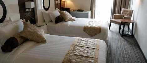 A hotel room with two beds, a nightstand, a chair, and a large window.