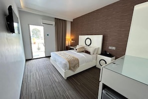A hotel room with a bed, a desk, a chair, a TV mounted on the wall, and a window. - Bei Boutique Hotel (Muar)