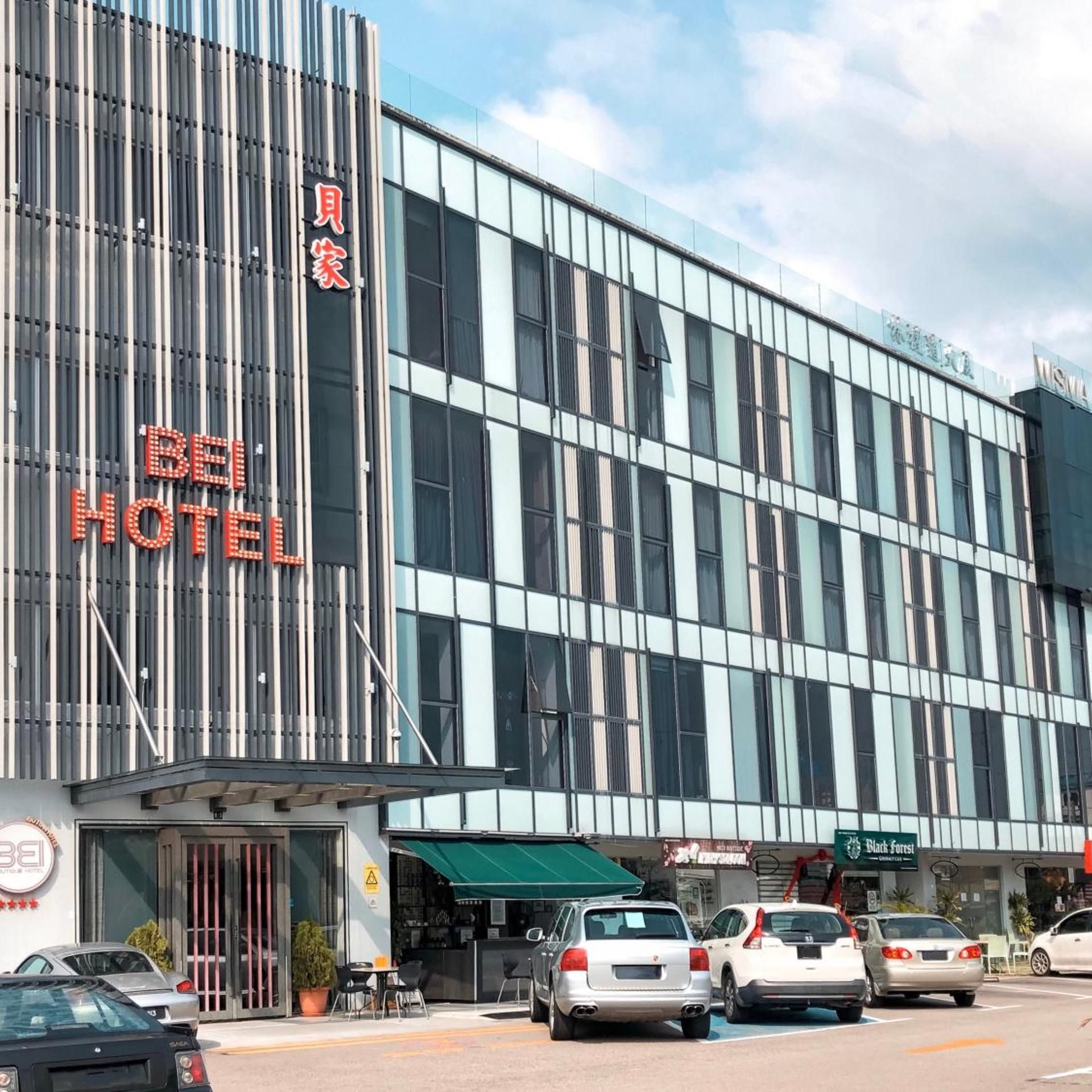 Un hôtel à la façade moderne, avec une entrée bien visible et plusieurs voitures garées devant.