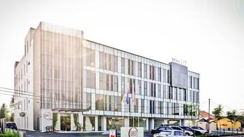 A modern building with a glass facade, a sign reading 'WSMA LLT', and multiple flags.