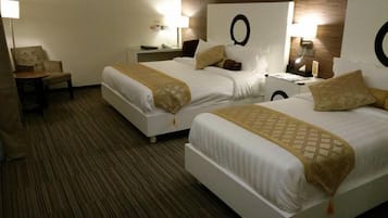 Ein Hotelzimmer mit zwei Betten, einem Sessel, einem Nachttisch und einer Lampe.