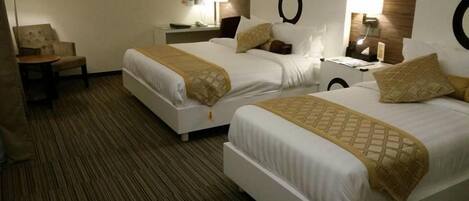 A hotel room with two beds, a chair, a nightstand, and a lamp.