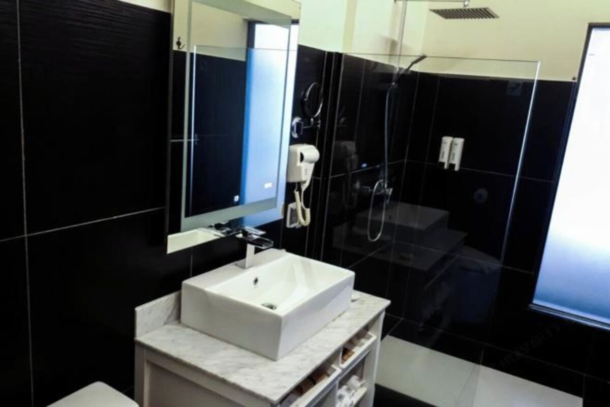 A modern bathroom with a white sink, a mirror, and a glass-enclosed shower.