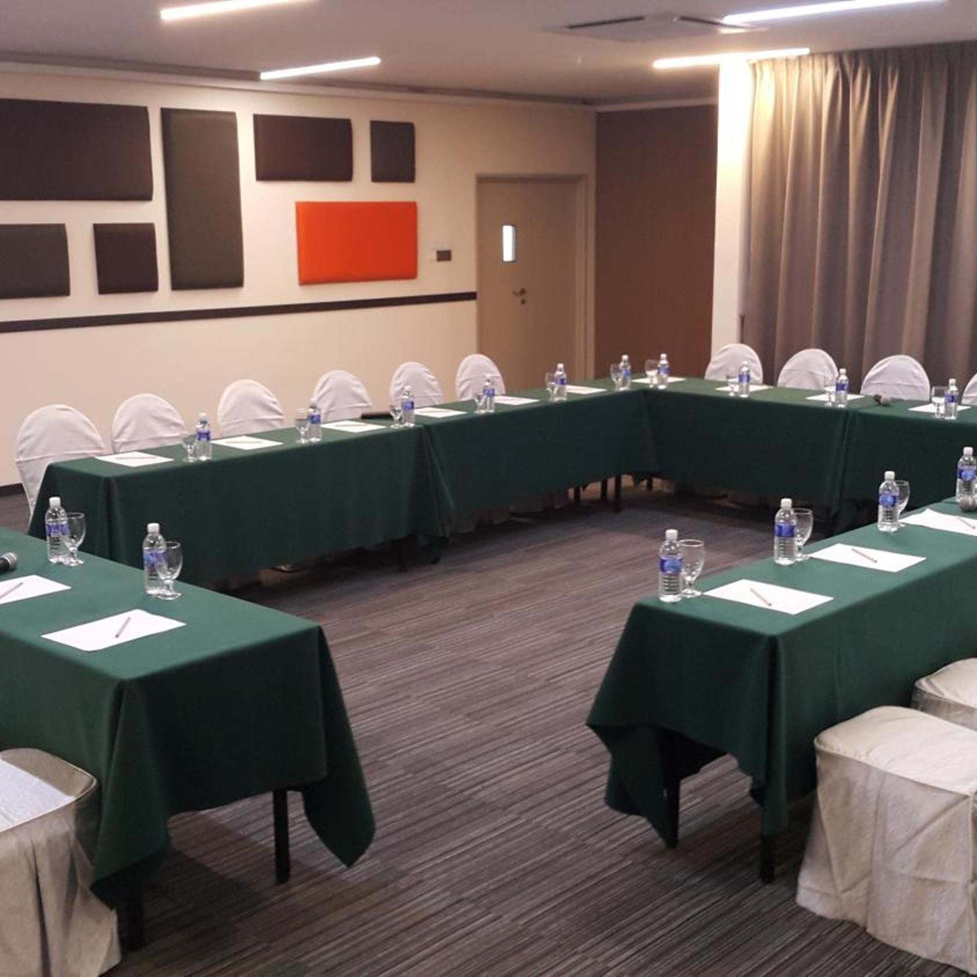 Ein Konferenzraum mit einem langen Tisch, Stühlen und Wasserflaschen.