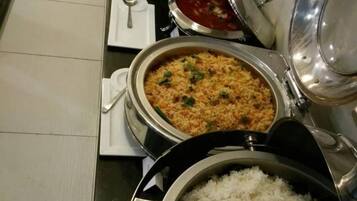 A buffet setup with various dishes including rice, a rice-based dish, and a red sauce.