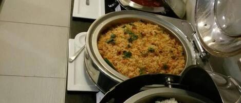 A buffet setup with various dishes including rice, a rice-based dish, and a red sauce.