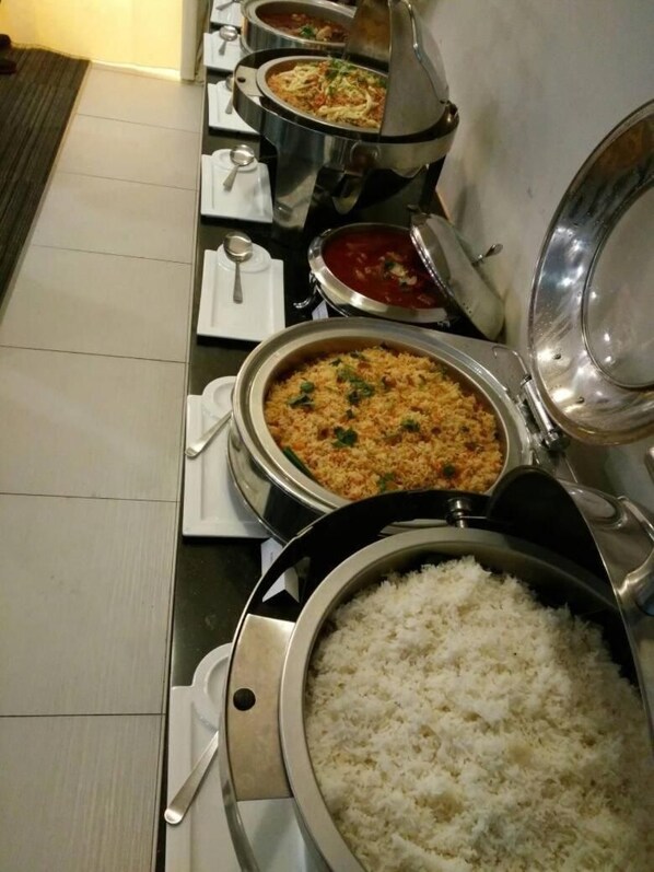 A buffet setup with various dishes including rice, a rice-based dish, and a red sauce.