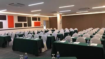 A conference room with rows of tables, each with a water bottle, glass, and notepad.