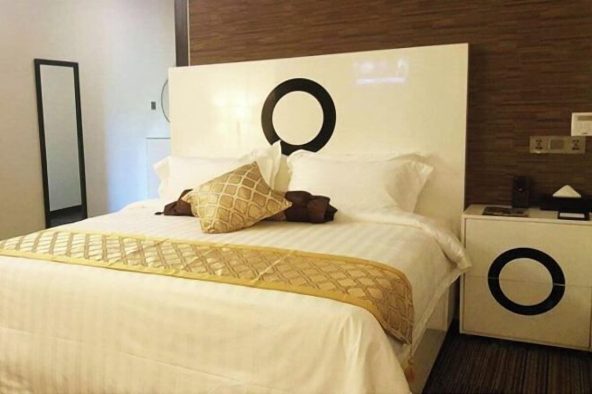 Ein Hotelzimmer mit einem großen Bett, einem Kopfteil mit kreisförmigem Design, einem Nachttisch mit kreisförmigem Design und einem wandmontierten Spiegel.