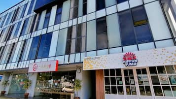 A modern building with a glass facade, a restaurant named 'NIPPON SUSHI' on the ground floor, and a sign for 'RESTORAN JAPON' above the entrance.