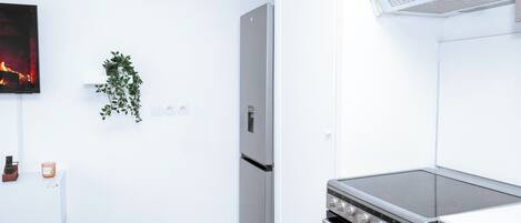 Una cocina moderna con horno empotrado, estufa de acero inoxidable y extractor de aire mural.