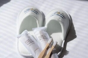 A pair of white slippers with a logo and text on them, placed on a white surface. - The Peak Tengachaya (Osaka)