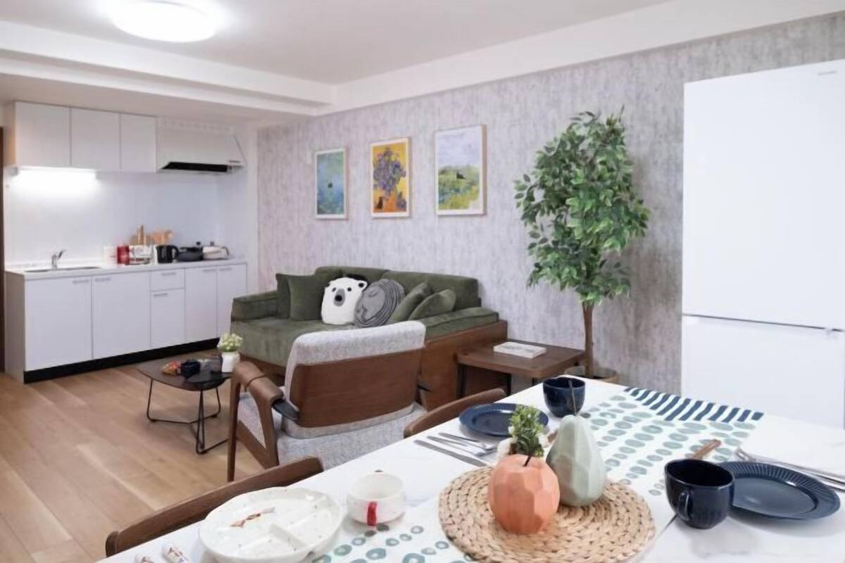 Een moderne woonkamer met een bank, eettafel en keuken op de achtergrond.
