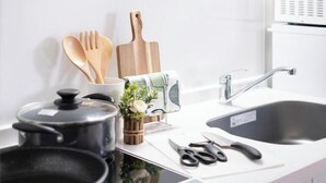 A kitchen with a sink, a pot, wooden utensils, and a plant. - The Peak Tengachaya (Osaka)