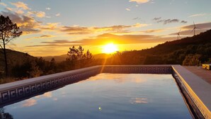 A swimming pool with a view of the sunset and wind turbines in the background. - Casa Alfarobeira, vila for 4P+baby with private pool in natural protect erea (São Bartolomeu de Messines)