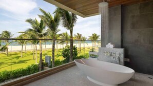 Un bagno moderno con una vasca da bagno ampia, vista sulla spiaggia e un design minimalista.