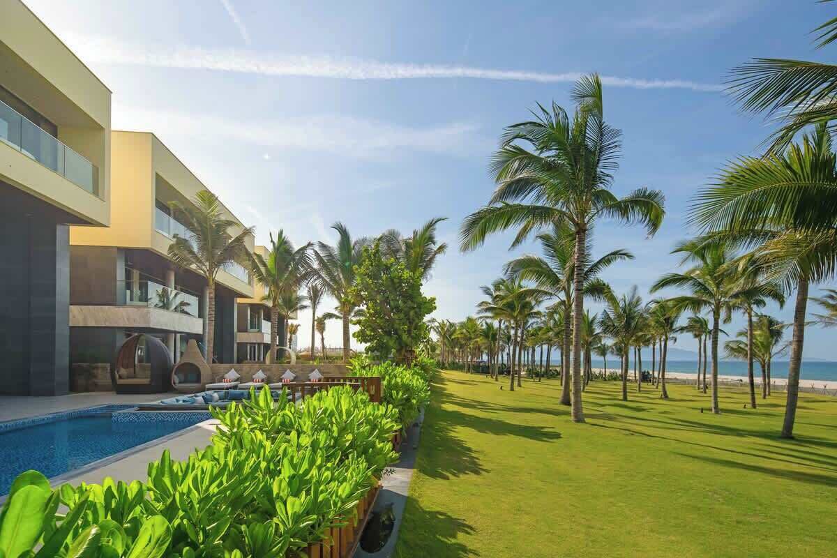 A resort with a swimming pool, palm trees, and a view of the ocean.