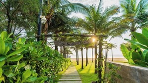 Un sendero que lleva a una playa con palmeras y un cartel que dice 'The Villa & Spa'.