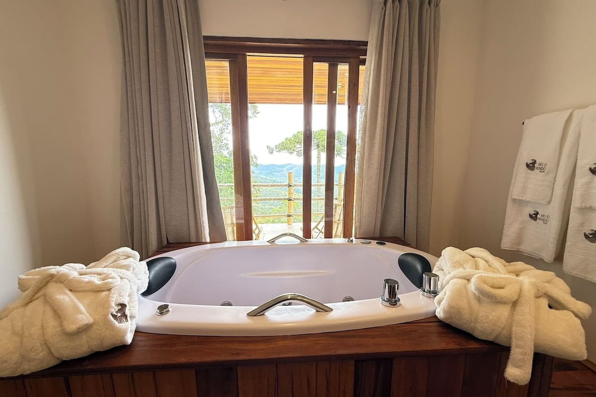 A bathroom with a large bathtub, two towels, and a view of the outdoors.