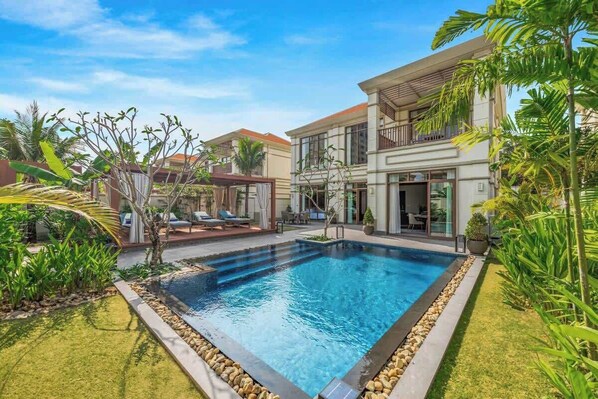 Relax by the pool surrounded by lush greenery and palm trees.