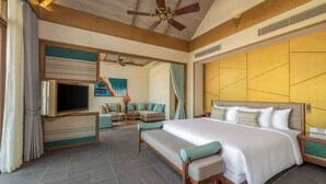 A spacious bedroom with a large bed, a TV, a sofa, and a ceiling fan.