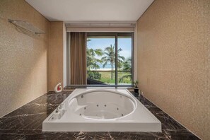 A modern bathroom with a large bathtub, a glass shower enclosure, and a view of palm trees and a beach. - 8BR Beachfront Eden: Luxury Events & Getaways (Da Nang)