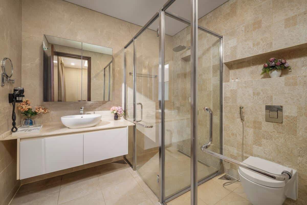 Un baño moderno con cabina de ducha de vidrio, un lavabo blanco y un inodoro.