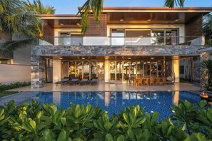 A modern two-story house with a swimming pool, outdoor seating, and tropical plants. - 8BR Beachfront Eden: Luxury Events & Getaways (Da Nang)