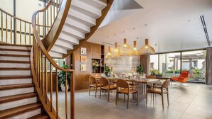 A modern interior with a spiral staircase, a dining area with wooden chairs, and pendant lighting.