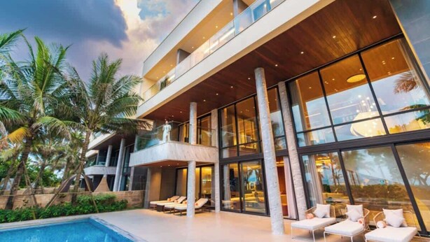 Ein modernes Hotel mit großem Pool, mehreren Balkonen und Palmen.