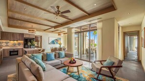 A spacious living area with a sofa, coffee table, and a rocking chair. There is a kitchen area with cabinets and a dining area with a table and chairs. - Luxe 5BR Villa: Beachfront Breakfast Pool (Da Nang)