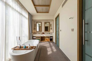 A modern bathroom with a freestanding bathtub, a vanity with mirrors, and a shower area.