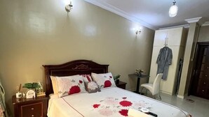 Une chambre à coucher avec un grand lit, une table de chevet, une armoire et un luminaire au plafond.