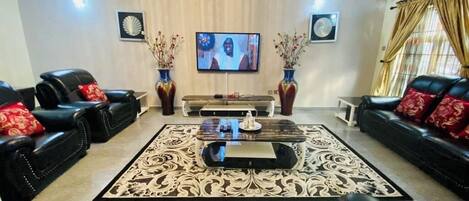 Relax in a stylish living room with a central sofa, two additional sofas, a coffee table, and a flat-screen TV.