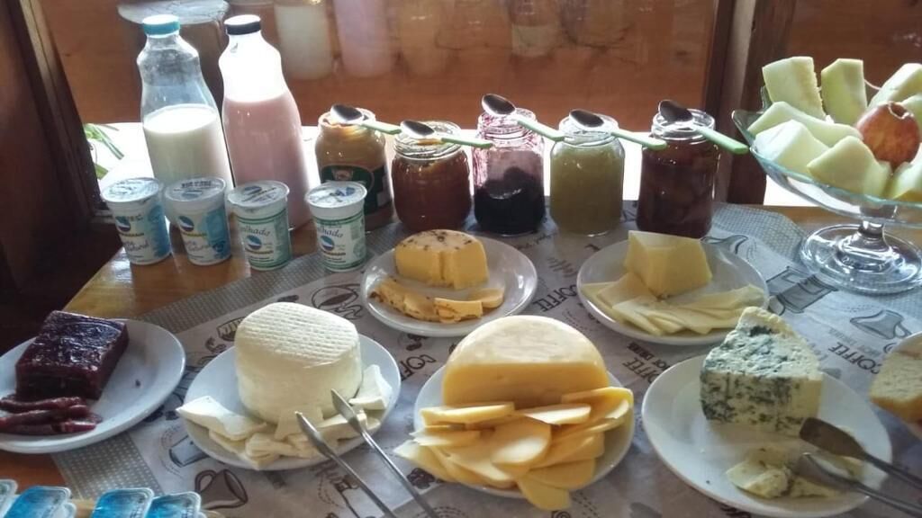 A table with various cheeses, butter, and jams.