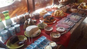 A buffet table with various food items including cakes, pastries, and condiments. - Pousada Pinhalense (Santo Antonio do Pinhal)