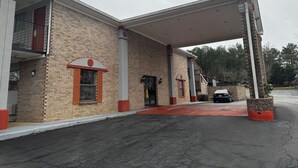 A brick building with a gas station canopy, a red awning, and a small brick planter. - Suni's Place (Union City)