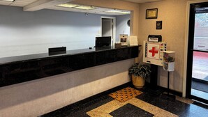 A reception area with a black marble counter, a potted plant, a red emergency exit sign, and a framed welcome sign. - Suni's Place (Union City)