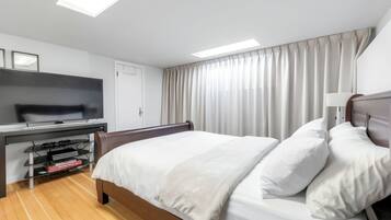 Een hotelkamer met een bed, een televisie, een bureau met een computer en een raam met gordijnen.