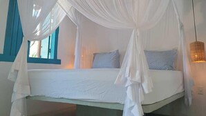 A bed with a white canopy, a woven light fixture, and a window with blue shutters. - Trancoso Biriba guest house (Porto Seguro)