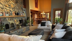A cozy living room with a stone fireplace, comfortable seating, and a dining area in the background. - Ugly Duckling Lodge - Swan Lake Retreat (Dalton)