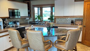 A modern kitchen with a central island, bar stools, and a dining table. - Ugly Duckling Lodge - Swan Lake Retreat (Dalton)